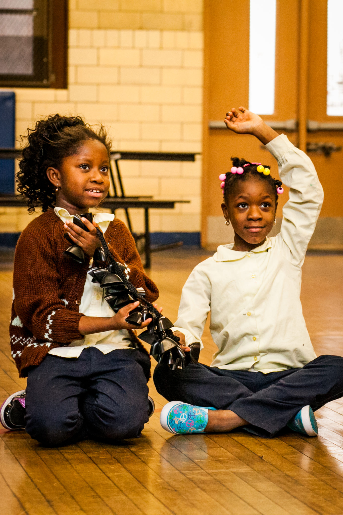 two girls hold an instrument during a presentation by in-facility artist Tony Mascara.