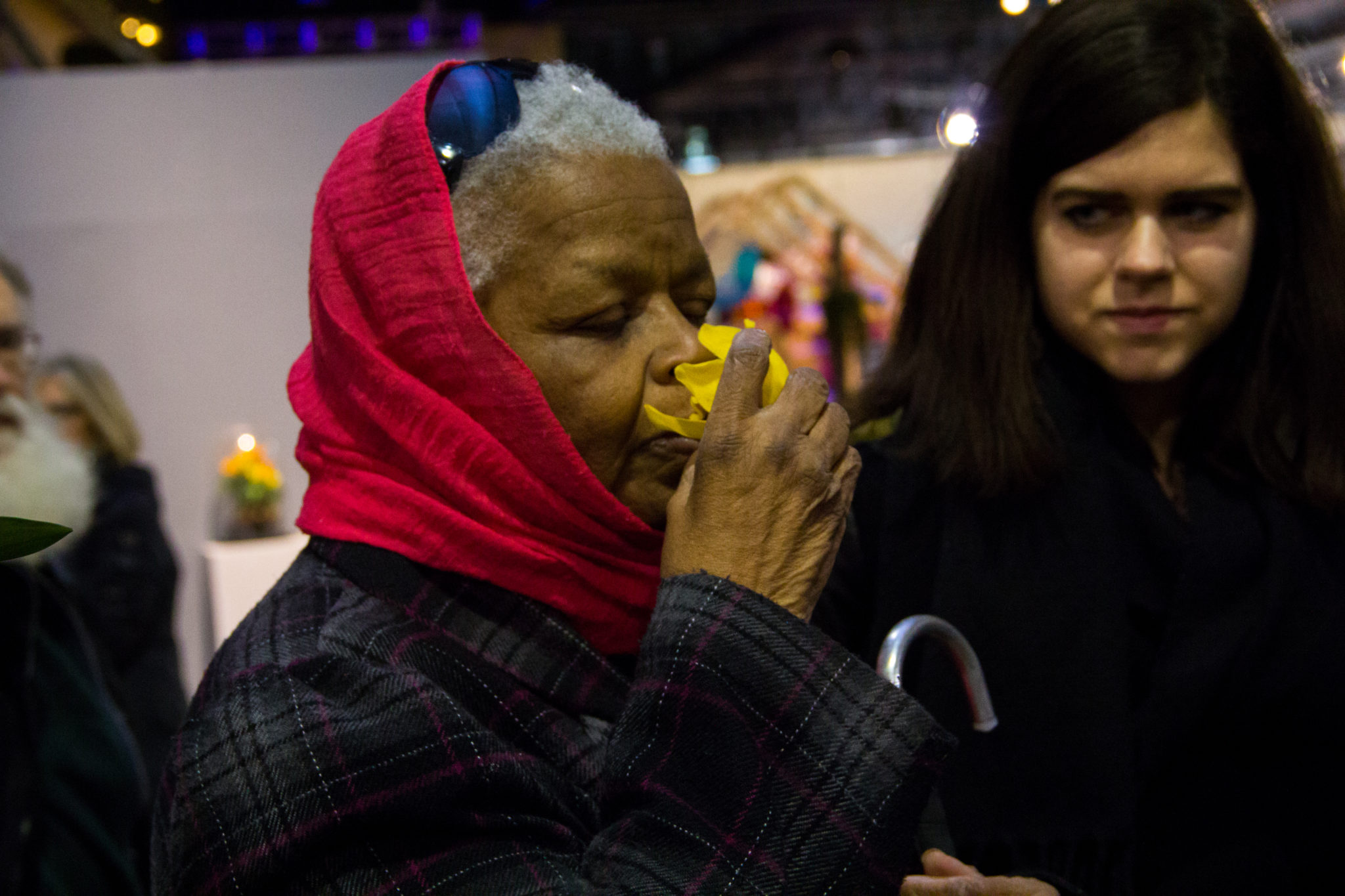 Member for Associated Services for the Blind smelling a yellow flower with big petals, at Art-Reach's 2017 audio described tour of the Philadelphia Flower Show.
