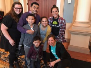 A group of people pose for a picture with Art-Reach volunteer Alanna Raffel at a Sensory-Friendly Sound All Around concert at the Academy of Music.