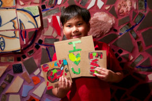 A child holds up mosaics he created at Philadelphia's Magic Gardens during an after school Encore event.