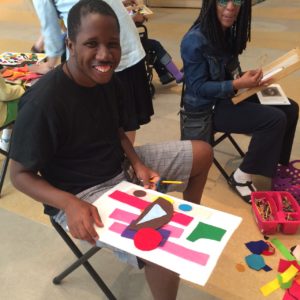A participant in one of Art-Reach's Encore events smiles while holding the artwork he created.