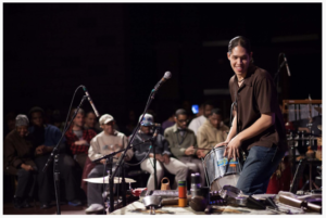 Live Connections performer Alex Shaw plays a drum at a concert.