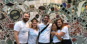Art reach staff posing infront of magic garden mosaics wearing matching art reach shirts