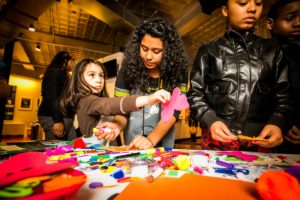 Three girls decorate paper butterflies.