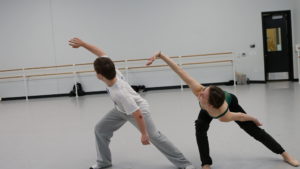 PA Ballet dancer and Saint Katherine Day School student dance together, lunging to the side on their right legs and extending their right arms diagonally to the side.