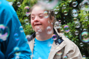 A person is surrounded by bubbles at Art Reach's 30th birthday party.