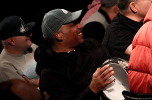 A man smiles while holding an instrument.