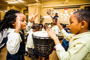Two girls drum at a presentation by Tony Mascara.
