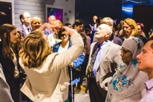 A group of blind visitors to the Franklin Institute listen to a woman performing an audio description.