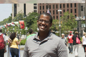 Lewis Johnson standing in front of the LOVE Statue with the packdrop of teh crowded parkway behind him