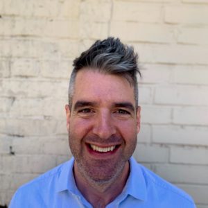 Photo of John Orr in front of beige brick wall