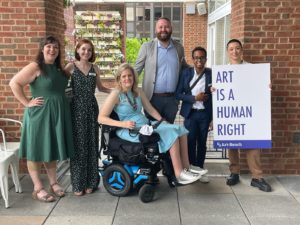 Art-Reach staff and intern pose for a photo at our 2022 Spring Brunch. One person is holding up a sign that reads "Art is a human right"