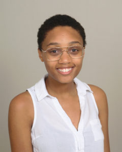 Black person with short black hair and white shirt. 