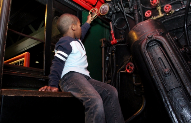 Child with brown skin playing with a valve in an interactive exhibition