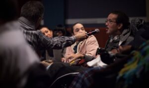 a person in a wheelchair being handed a microphone to speak to a group