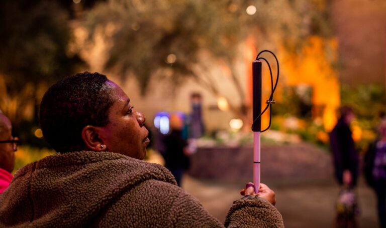 person with dark skin and short coiled hair holding a mobility cane