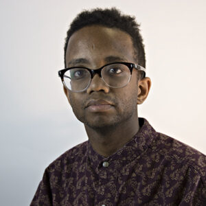 Julian Harper, a black person with brown skin short curly hair wearing a red long-sleeve shirt
