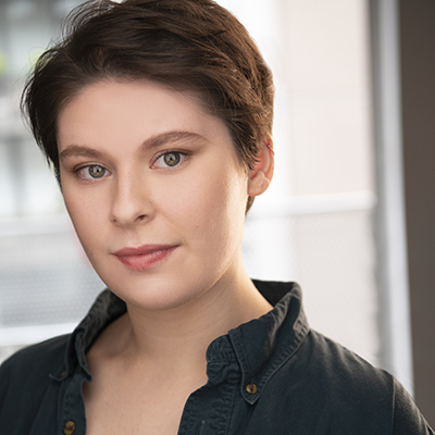Maggie Brennan, a white person with short brown hair wearing a black shirt